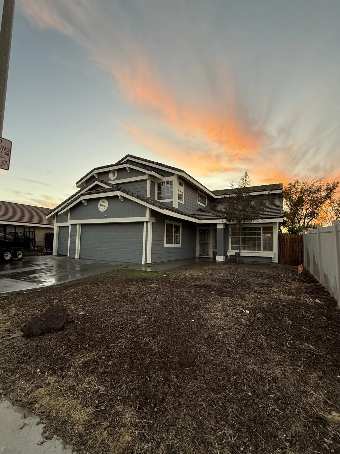 Two-story home exterior with painted siding and trim beneath a sunset sky